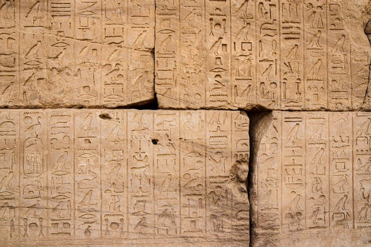 Close-up of intricate ancient Egyptian hieroglyphs carved into a stone wall, showcasing historical art.